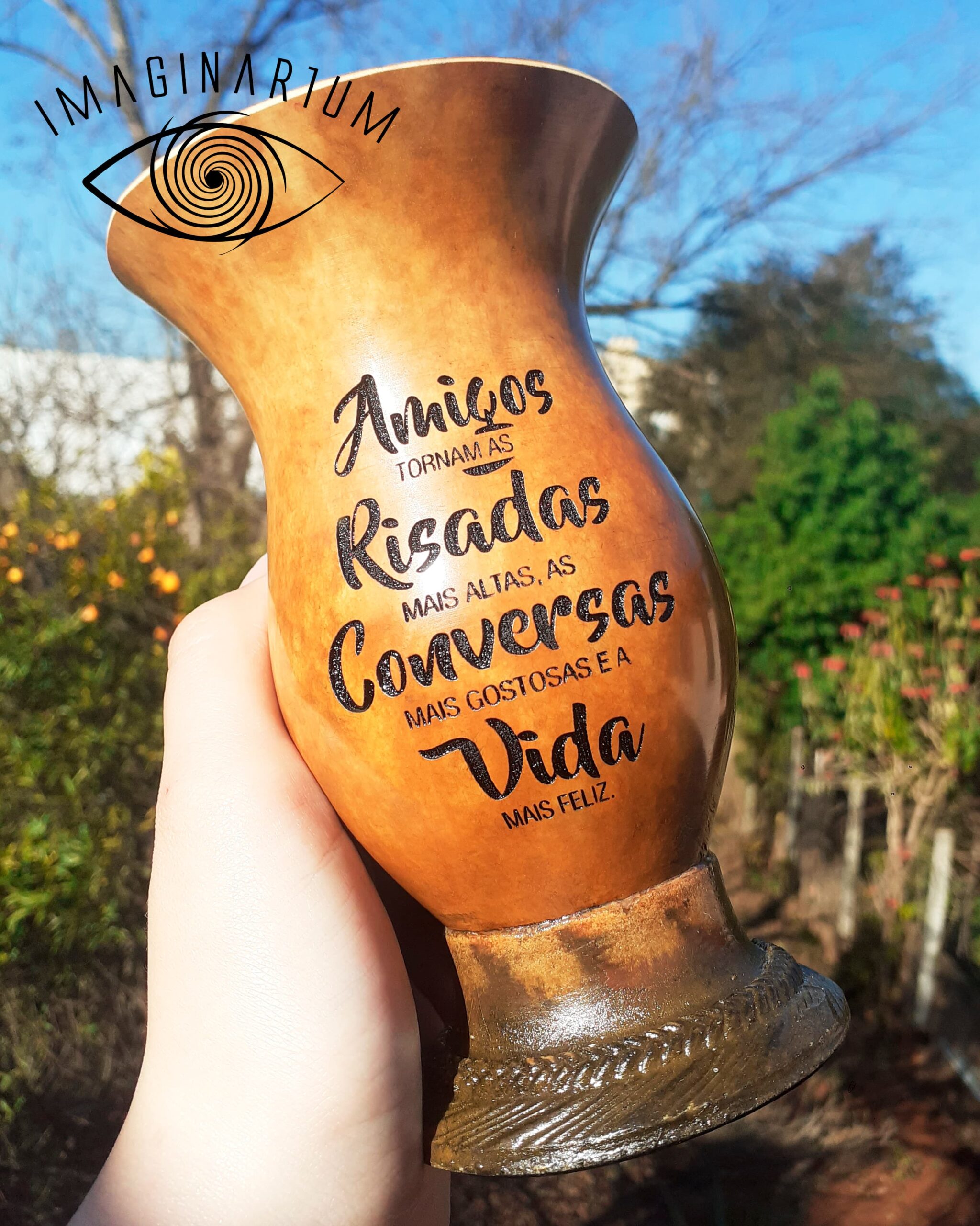 Cuia de chimarrão personalizada com frase, amigos tornam as risadas mais altas, as conversas mais gostosas e a vida mais feliz, com fundo ambiente de árvores